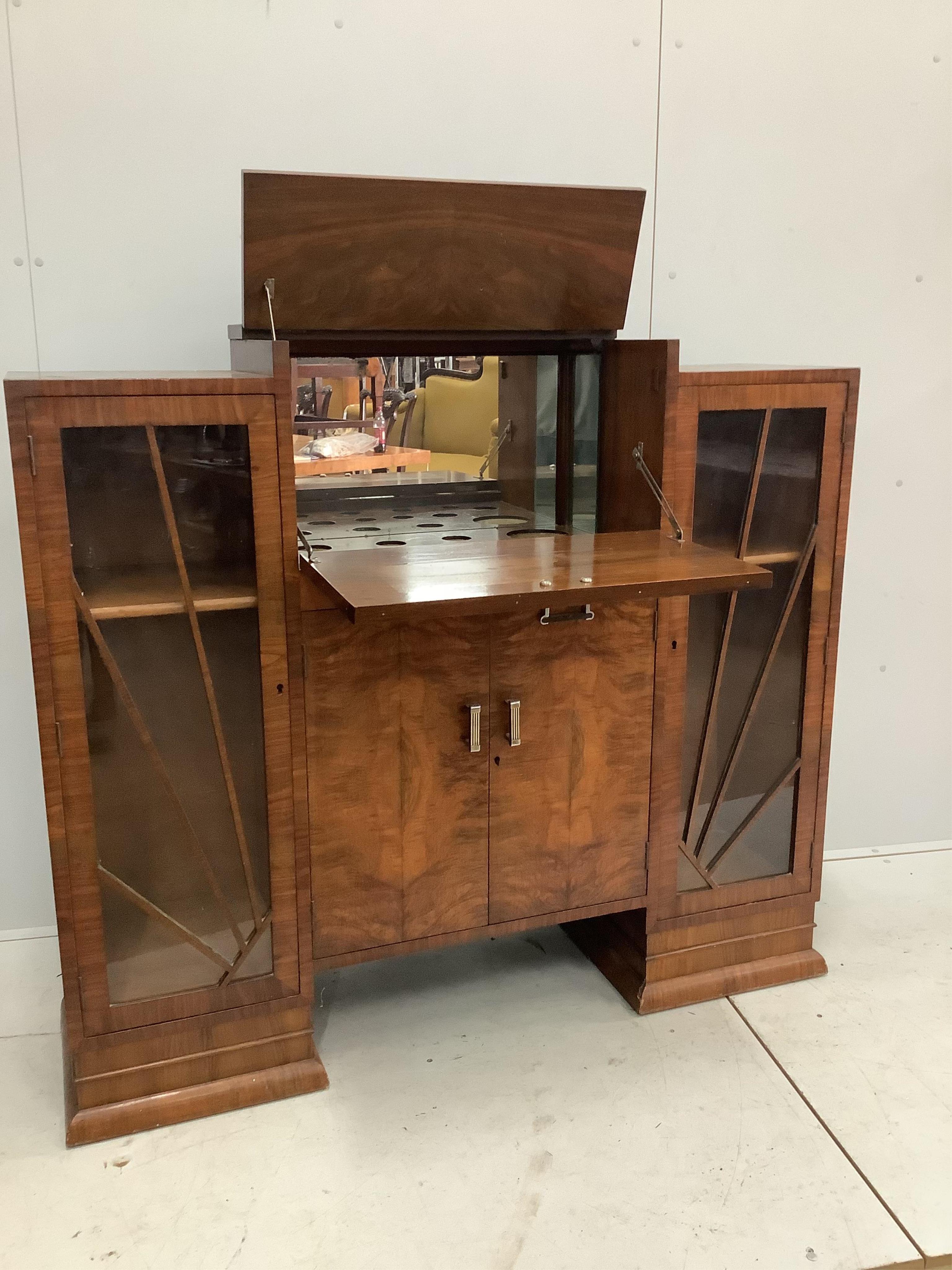 An Art Deco figured walnut cocktail cabinet, width 136cm, depth 39cm, height 123cm. Condition - one glass panel missing, otherwise fair